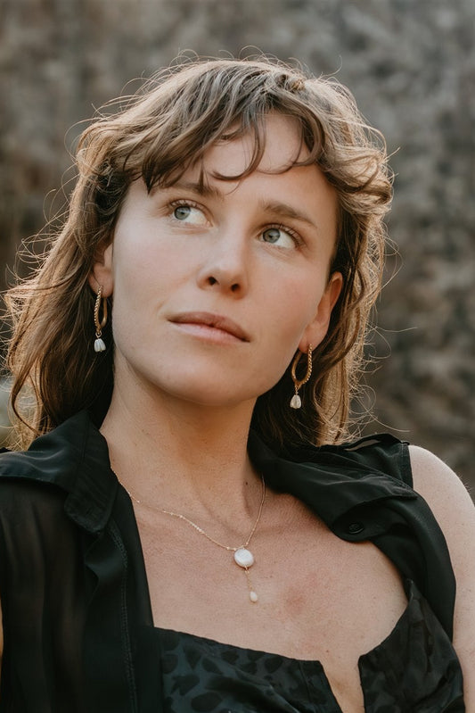 Woman in a black dress sitting on a rock with a natural background