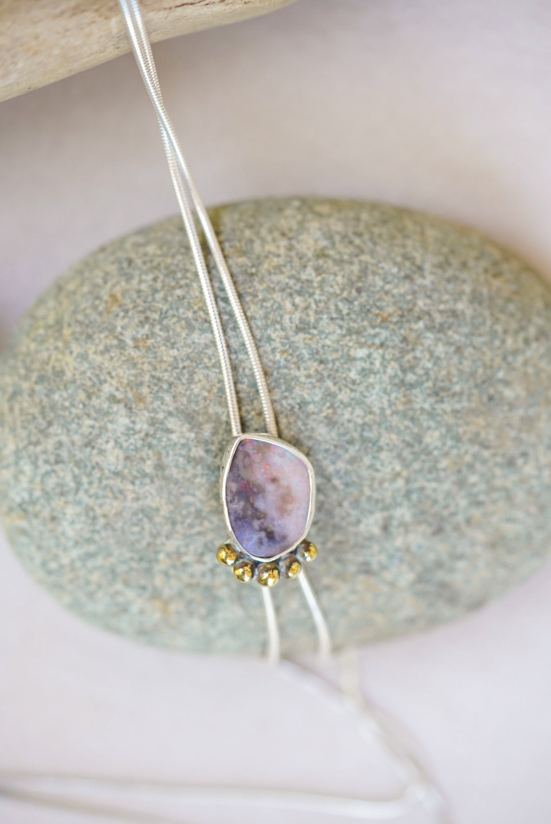 Bolo Opal Necklace with a pendant on a stone surface