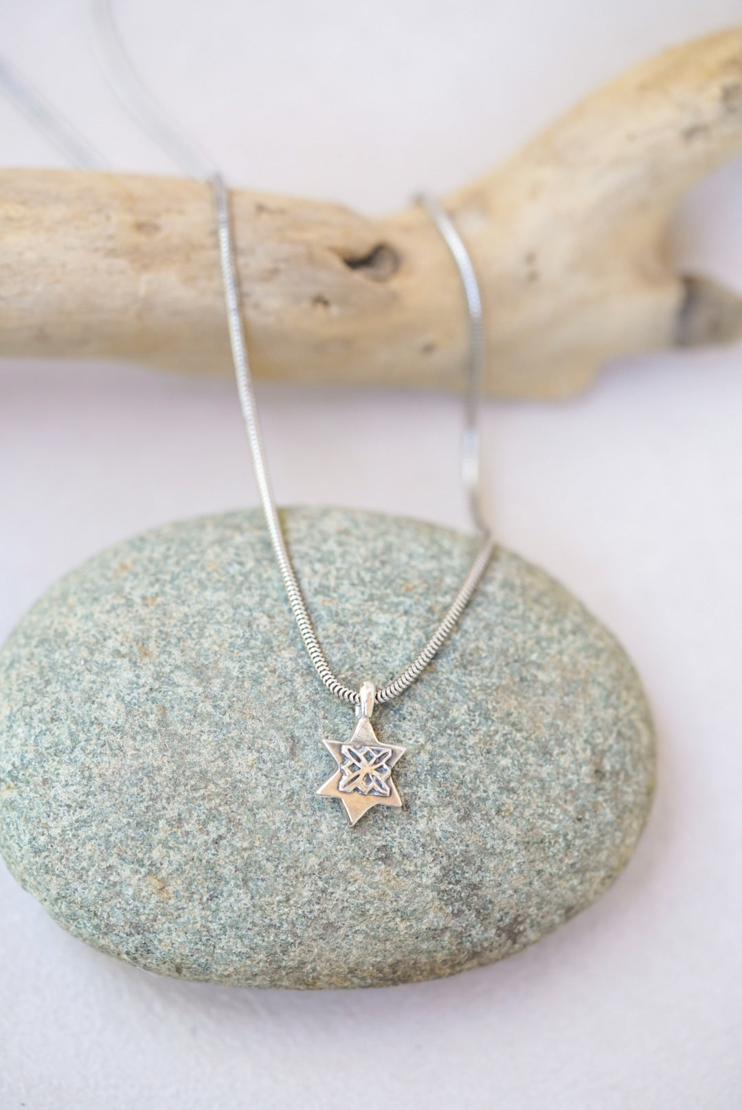 Silver necklace with a star pendant on a stone surface
