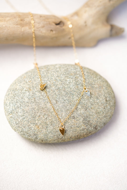Gold necklace with sequin pendants on a stone surface