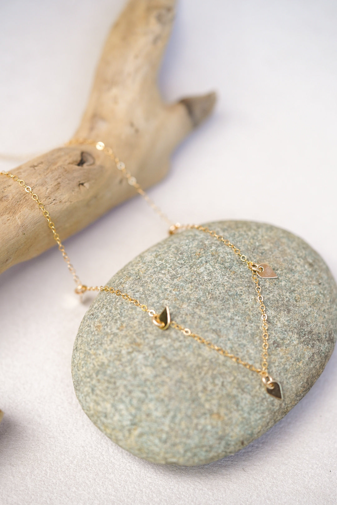 Gold necklace with sequin pendants on a stone surface
