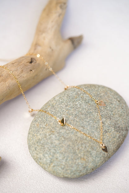 Gold necklace with sequin pendants on a stone surface