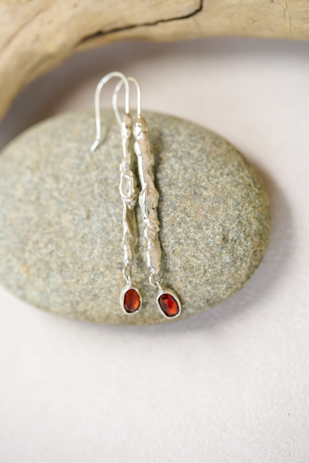 Silver earrings with red stones on a stone surface