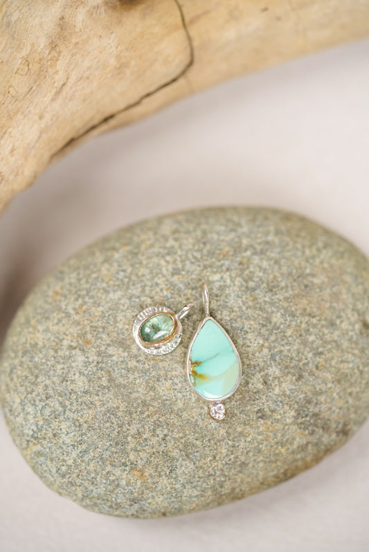 Teardrop-shaped turquoise pendant on a stone surface
