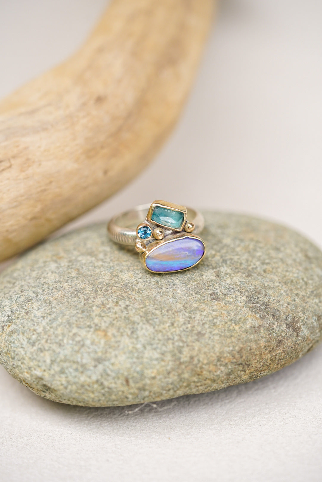 Ring with opal and blue gemstone on a stone surface