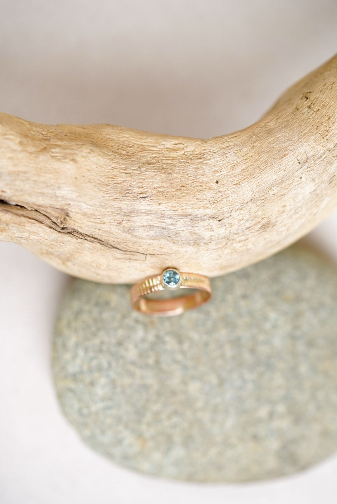 Montana sapphire gold ring next to a piece of driftwood