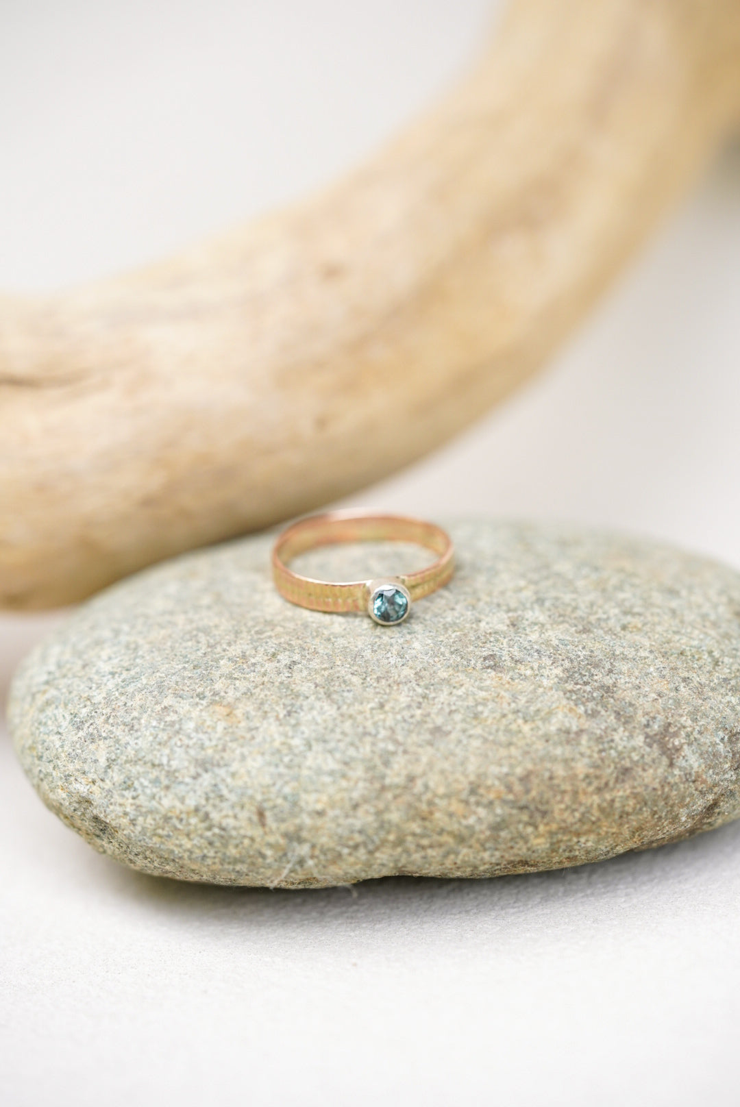 Montana sapphire gold ring next on a river rock