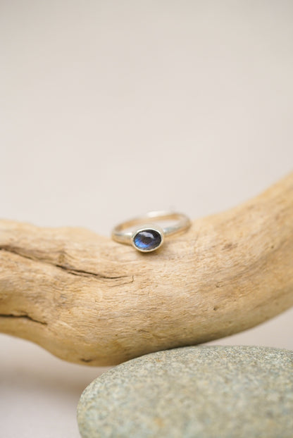 labradorite silver ring against a piece of driftwood