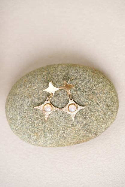 Gold earrings with star designs on a stone