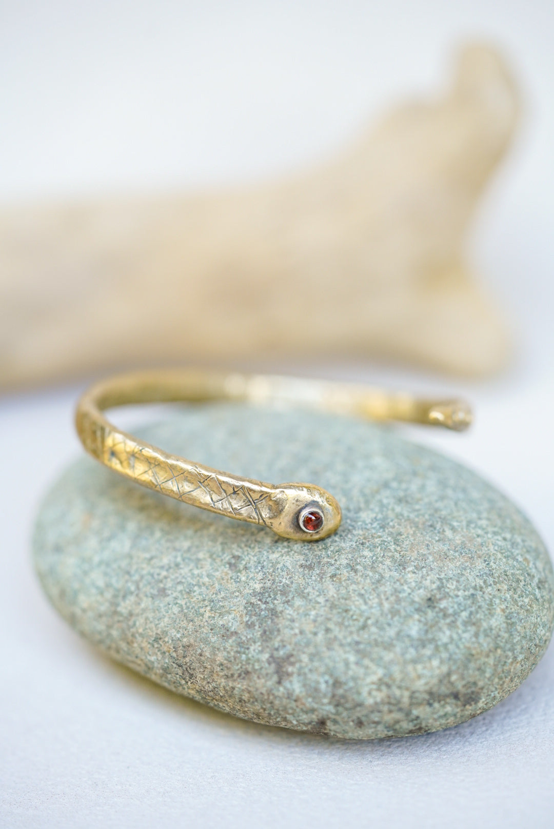 Gold bracelet with a red gemstone on a textured stone surface