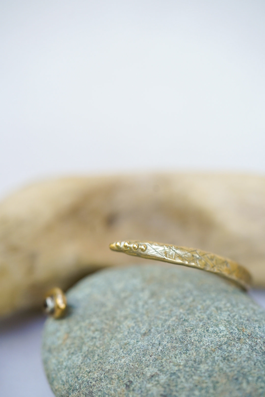 Gold bracelet on a stone surface with a blurred background