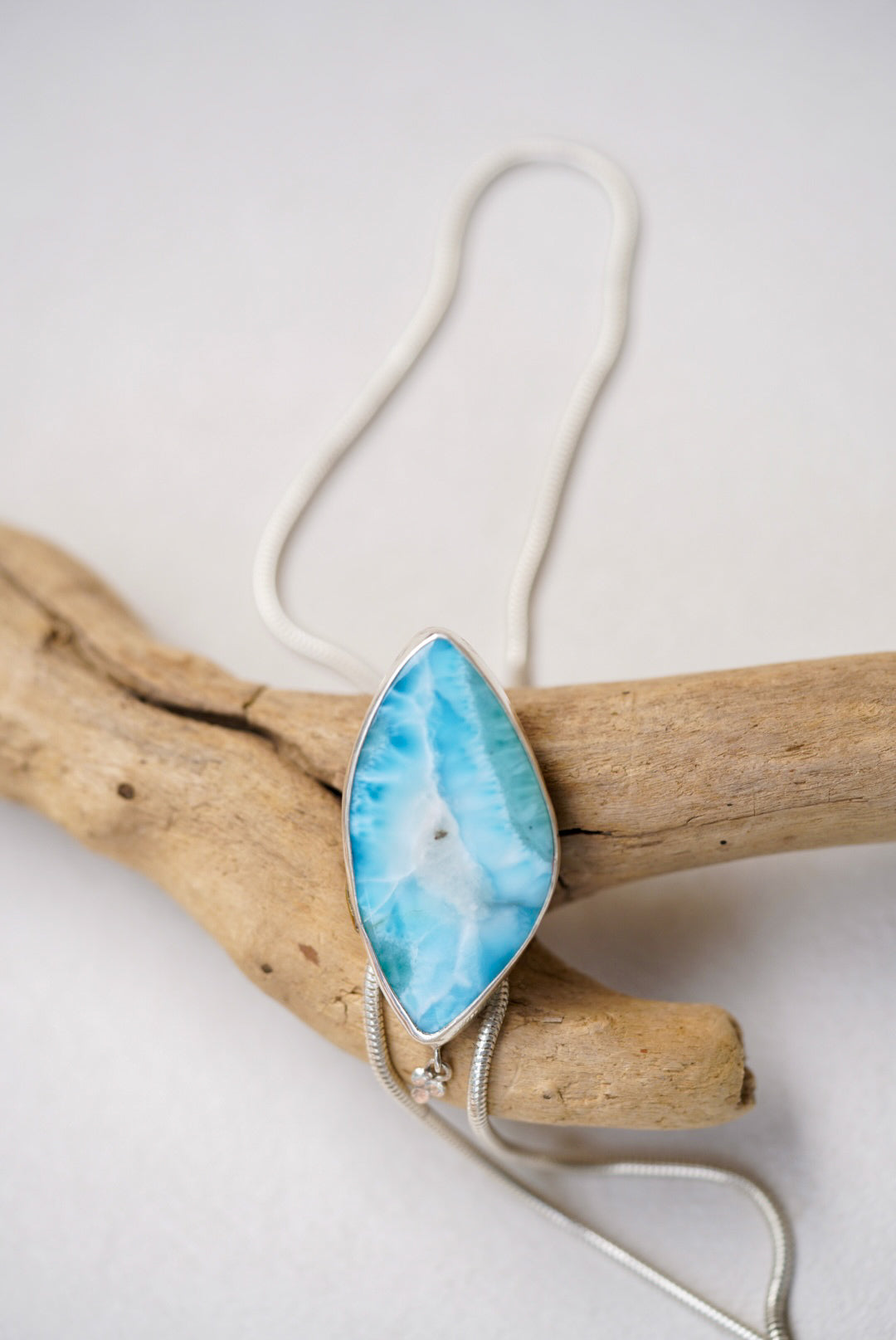 Large blue stone bolo necklace on top of a piece of driftwood