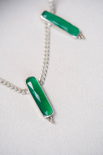 Two green pendant necklaces on a light gray background