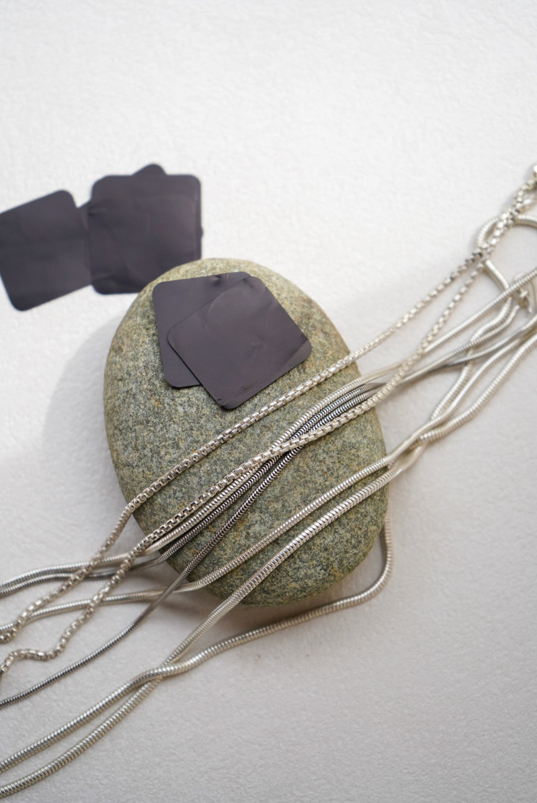 Anti tarnish tabs against silver chains atop a river rock