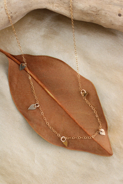 Gold necklace with gold pendants on a brown leaf and stone background