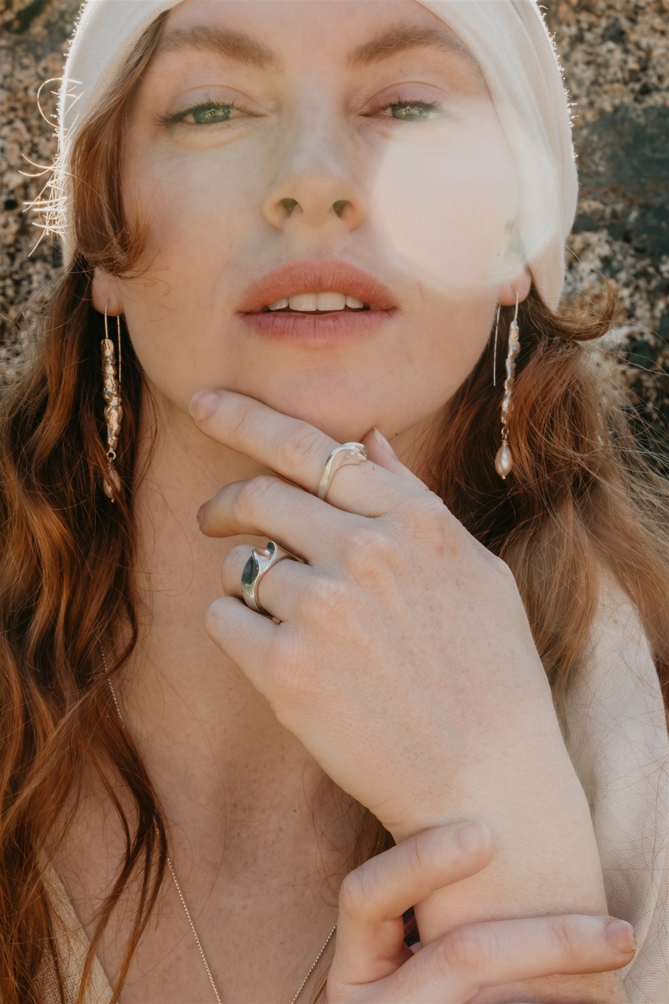 Woman with  silver earrings and rings, with a blurred background.