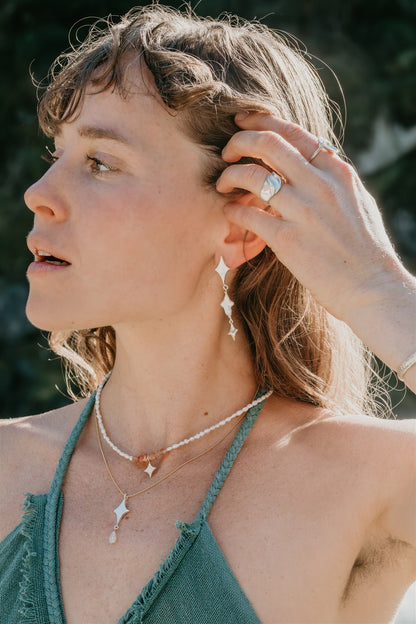 Woman outdoors with a blurred natural background, wearing jewelry