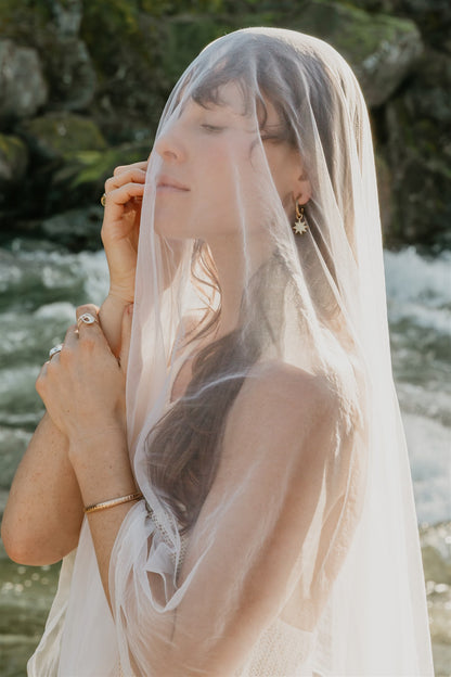Woman wearing a veil and jewelry with a natural background
