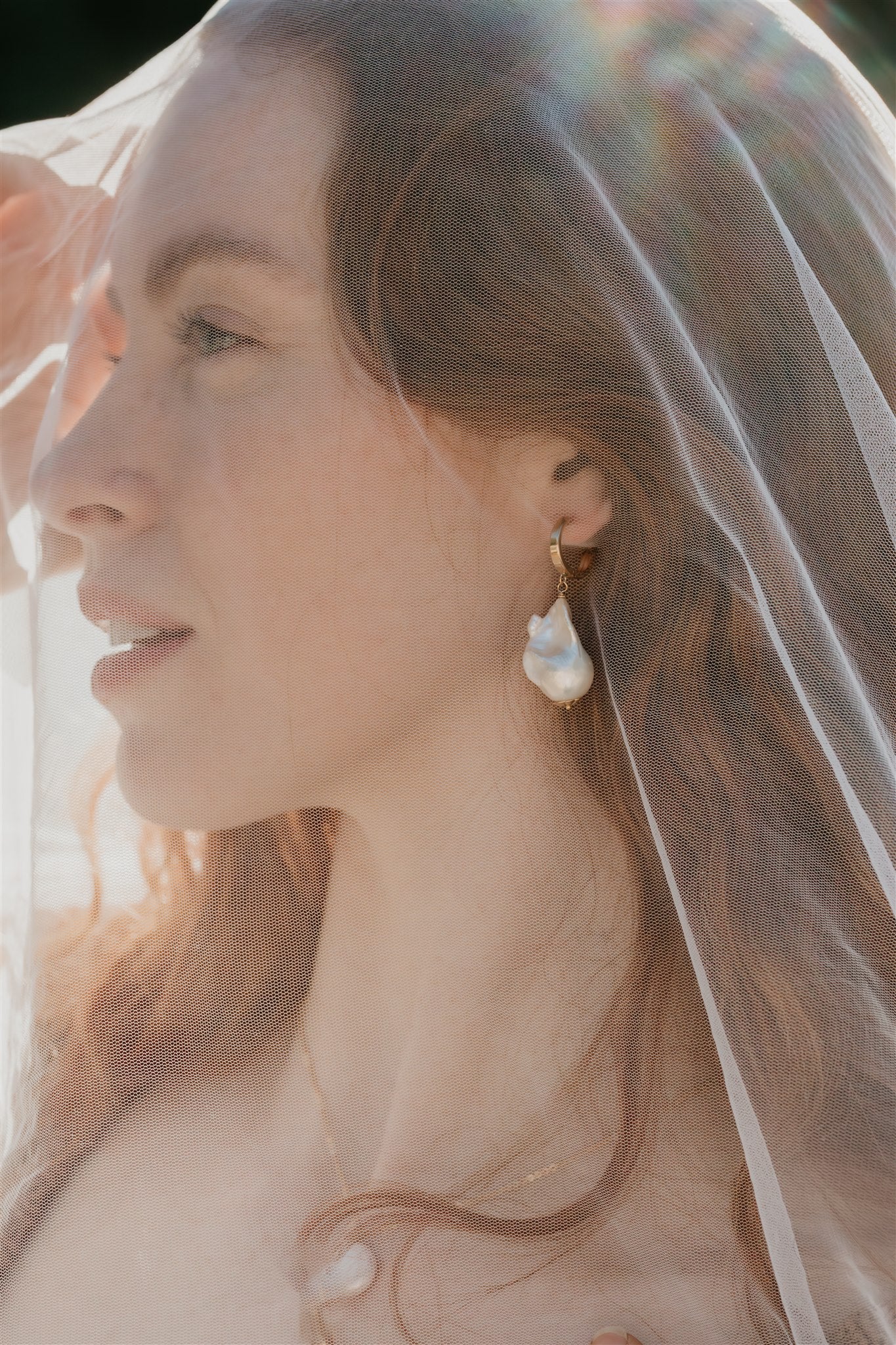 Woman wearing a veil with a soft, blurred background and pearl earring