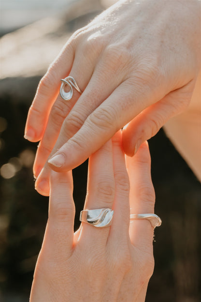 Close-up of two hands with silver rings on a blurred background