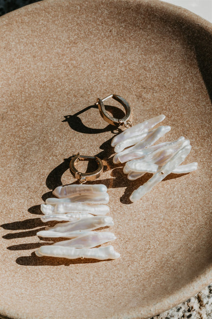 Pair of earrings with pearls on a beige surface