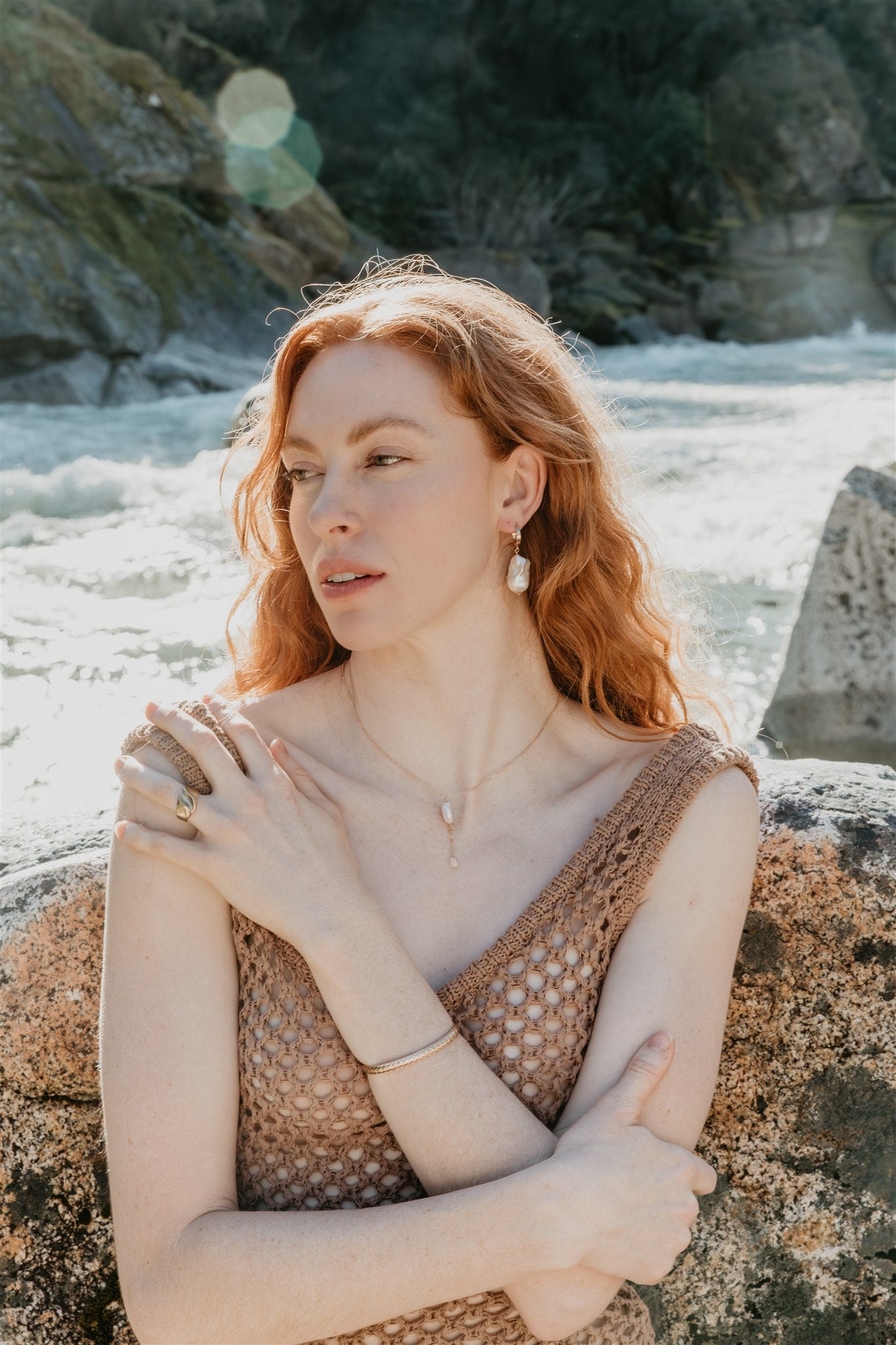 Woman with full jewelry on a rocky beach