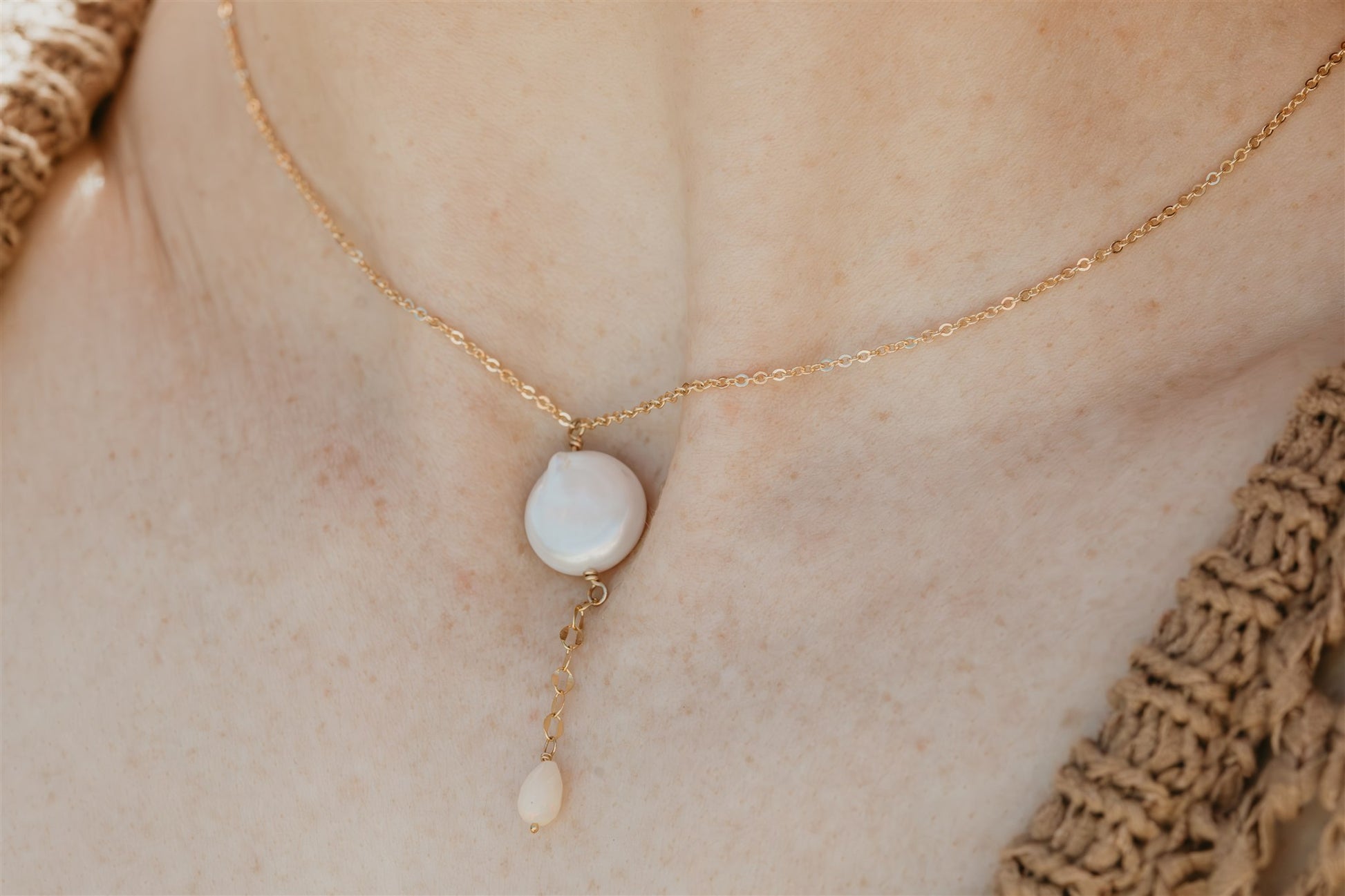 Gold necklace with a pearl pendant on a person's neck