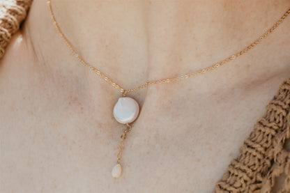 Gold necklace with a pearl pendant on a person's neck