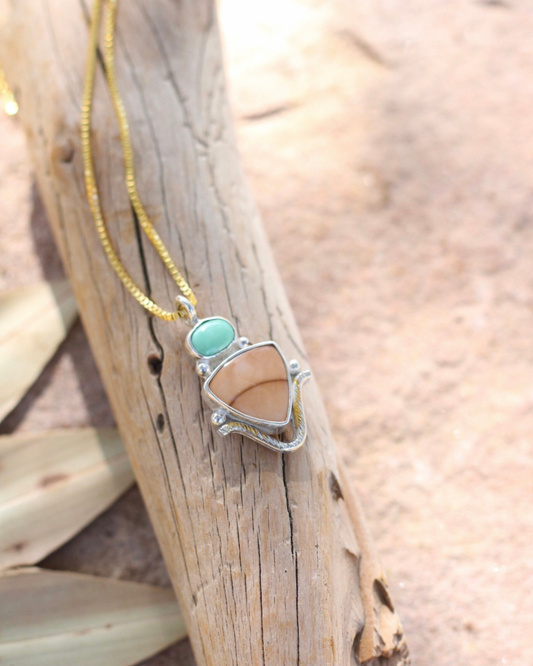 Necklace with a pendant featuring a turquoise and jasper stone on a wooden surface