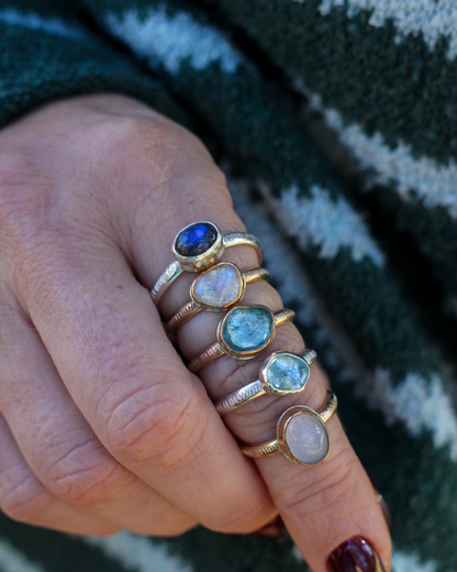 Close-up of a hand wearing multiple rings with gemstones against a striped fabric background